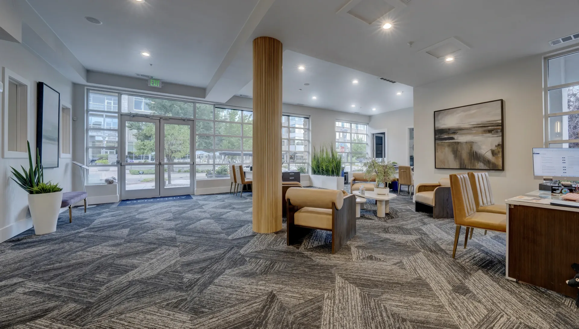 Modern apartment building lobby with large windows, comfortable seating, and a reception desk.