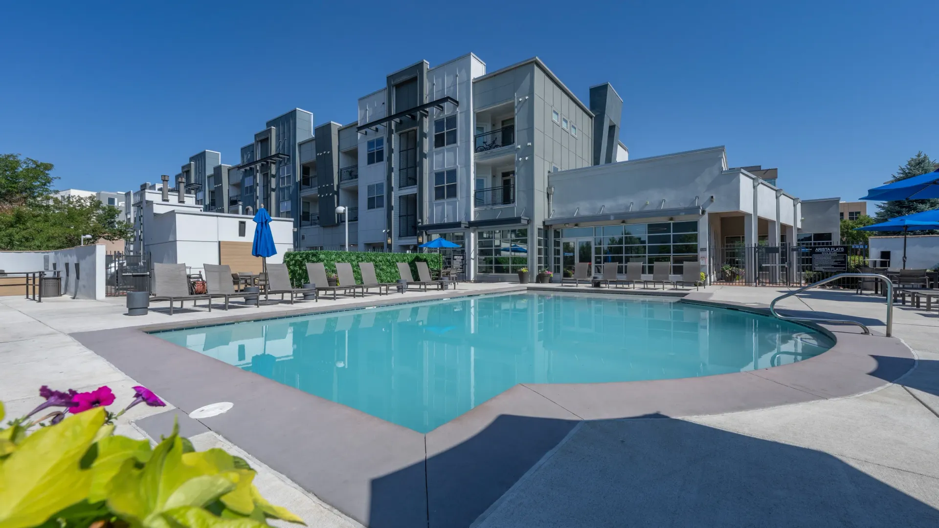 Modern apartment building with a large, inviting swimming pool and lounge chairs.
