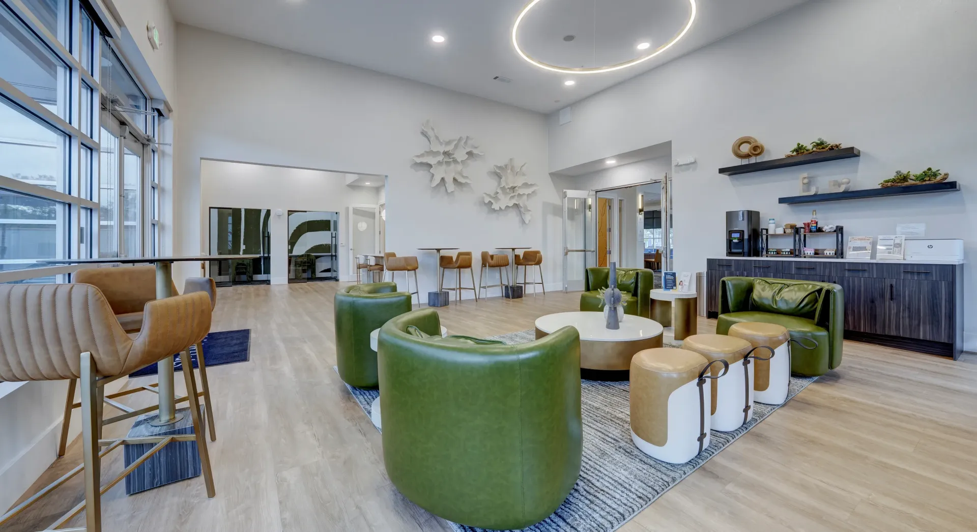 Modern lounge area with green chairs, white tables, and high bar seating.
