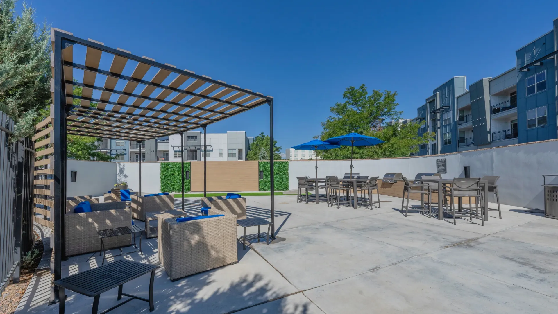 Outdoor patio area with lounge seating, tables, umbrellas, and grills.