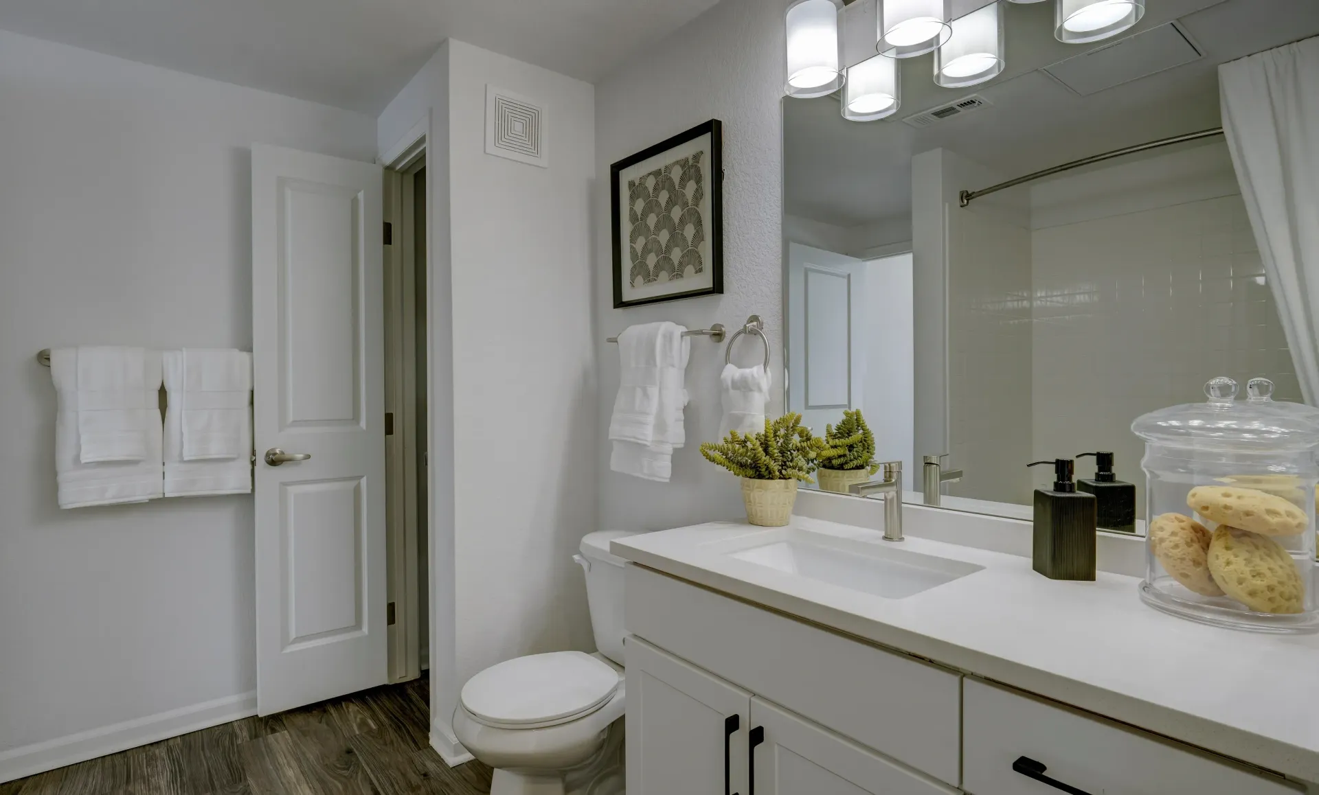 Modern bathroom vanity with white countertop, stainless steel faucet, and white cabinetry.