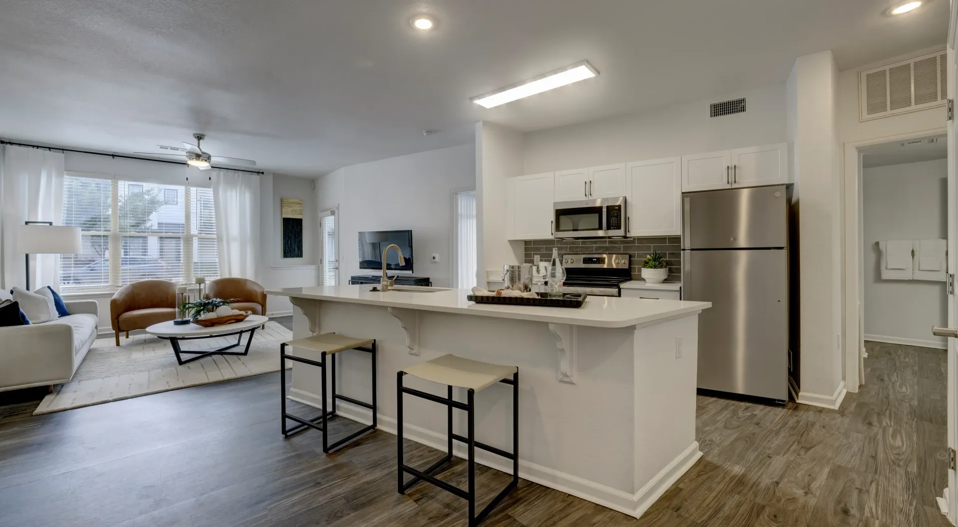 Modern kitchen and living area with island, bar stools, sofa, and chairs.
