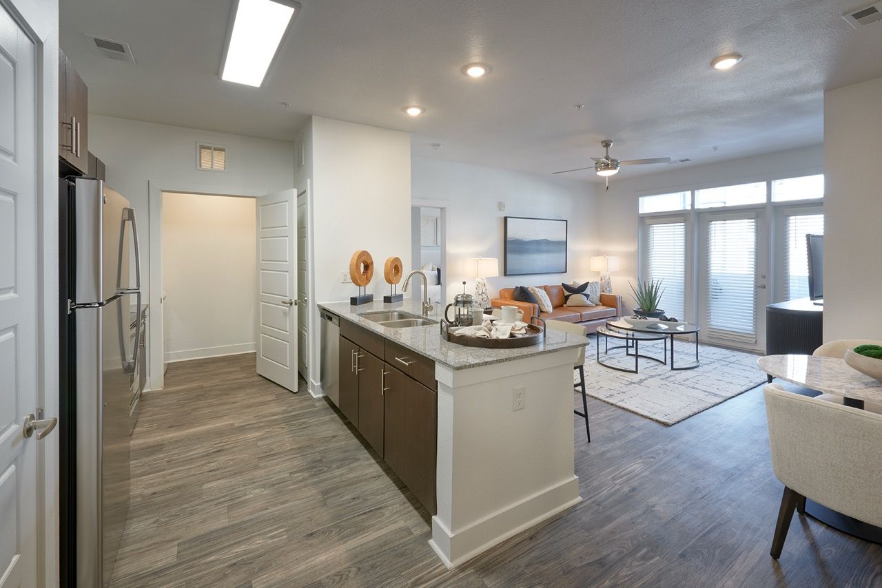 Open-concept kitchen and living area with island and large windows in a modern apartment.