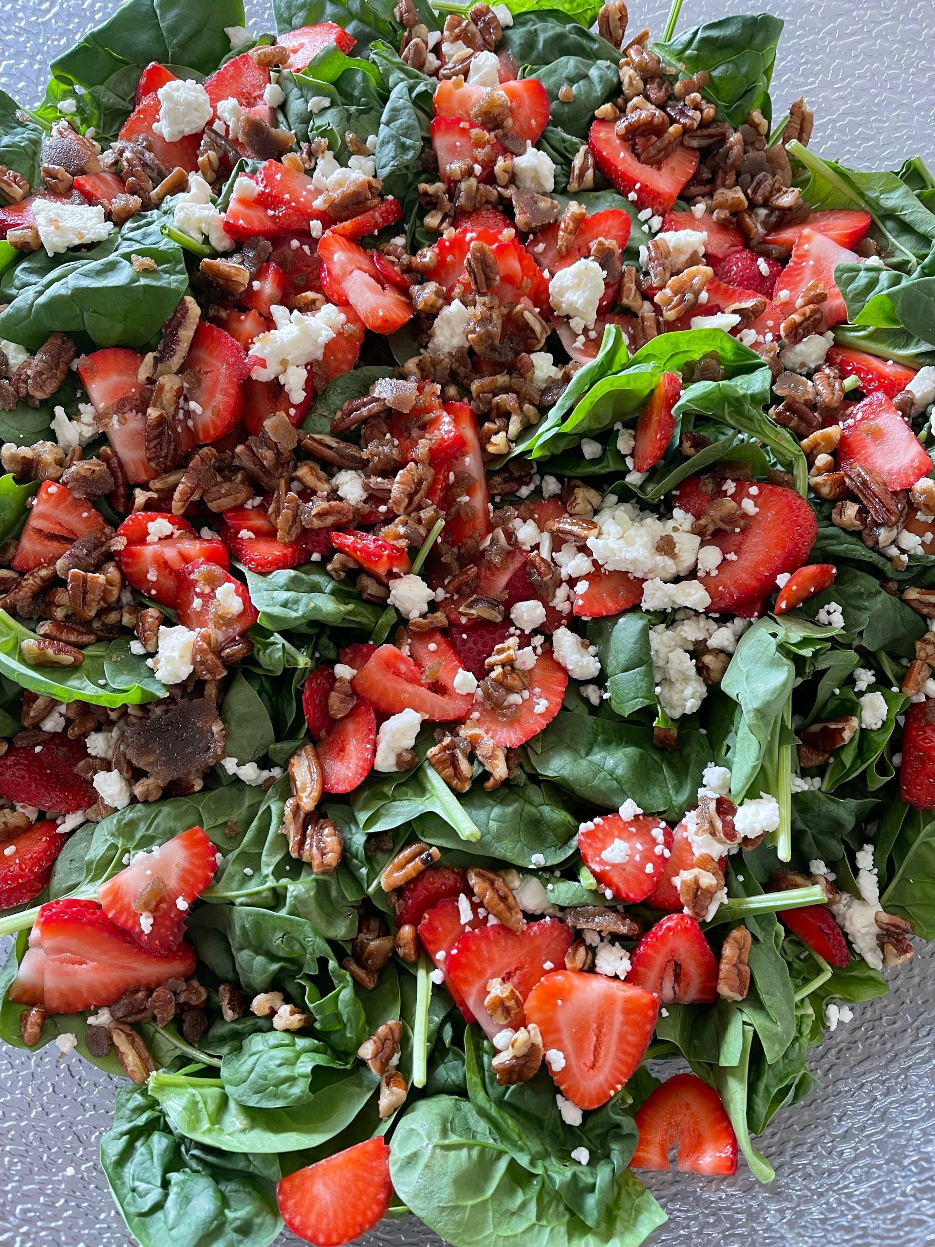 Mixed green salad with strawberries, crumbled cheese, and red peppers on a plate