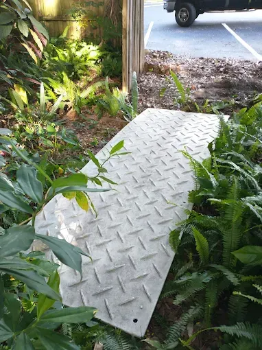 A metal ramp on a grassy area leading to a parking lot.