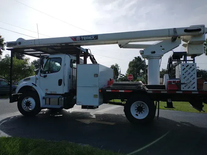 White Terex utility truck with an extended boom, parked on pavement.