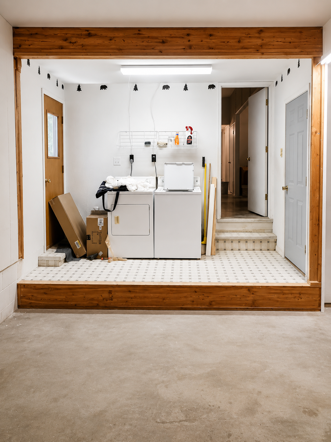 Unfinished room with white cabinets and sink, framed by exposed wood trim and a bare concrete floor.