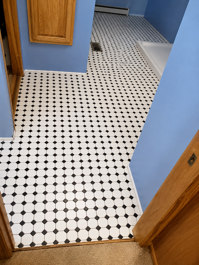 Blue hallway with white-and-black patterned tile floor and wooden door frames