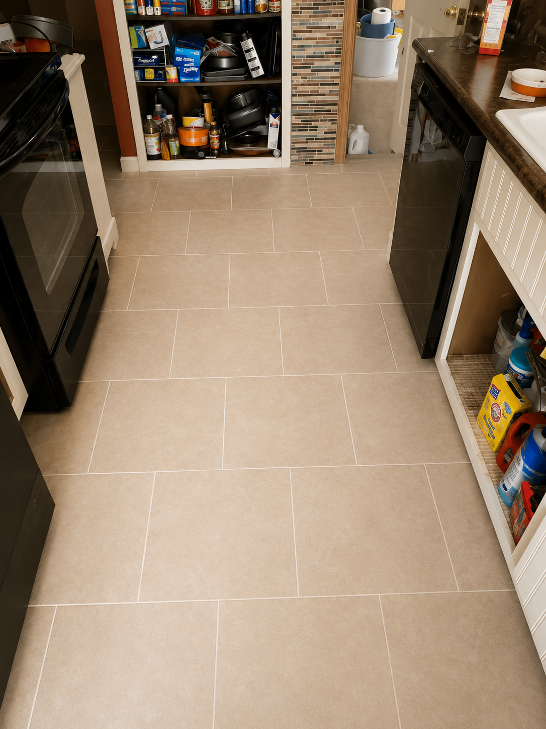 Narrow kitchen aisle with beige tile floor, open cabinets, and a stove on the left.