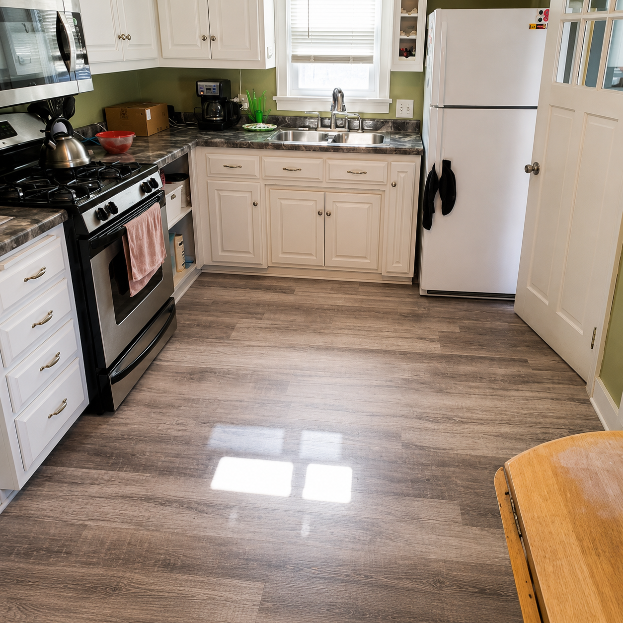 Bright kitchen with white cabinets, black stove, wood floor, and white refrigerator.