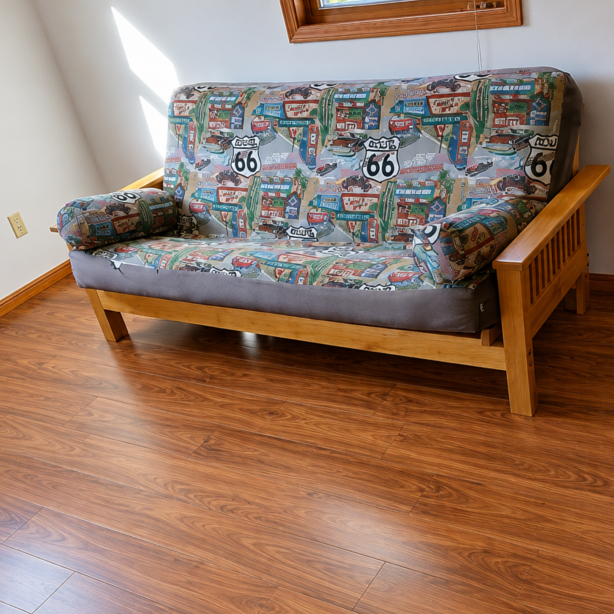 Patterned futon sofa with Route 66 print in a sunlit room with wood flooring