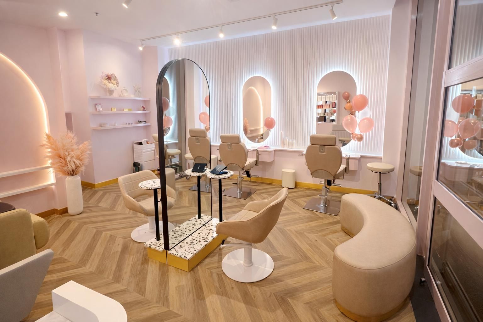 A chic salon interior featuring a central double-sided mirror, beige swivel chairs, a curved bench, and soft pink decor.