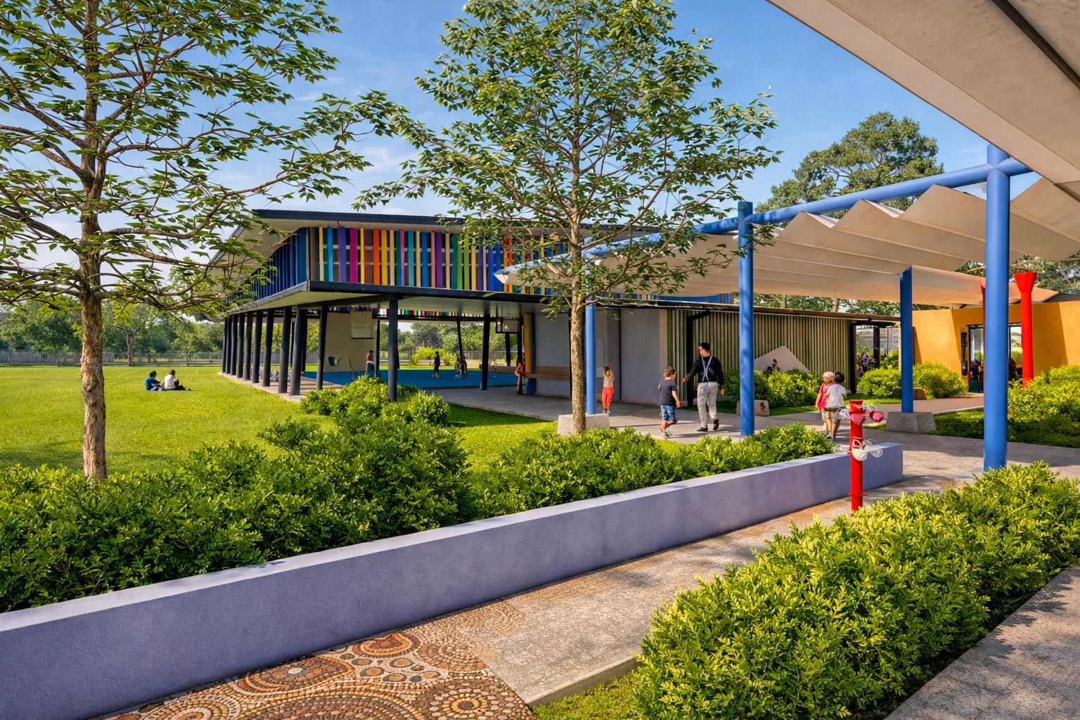 A vibrant, modern school building with colorful pillars beside a green field, shaded walkways, and garden landscaping.