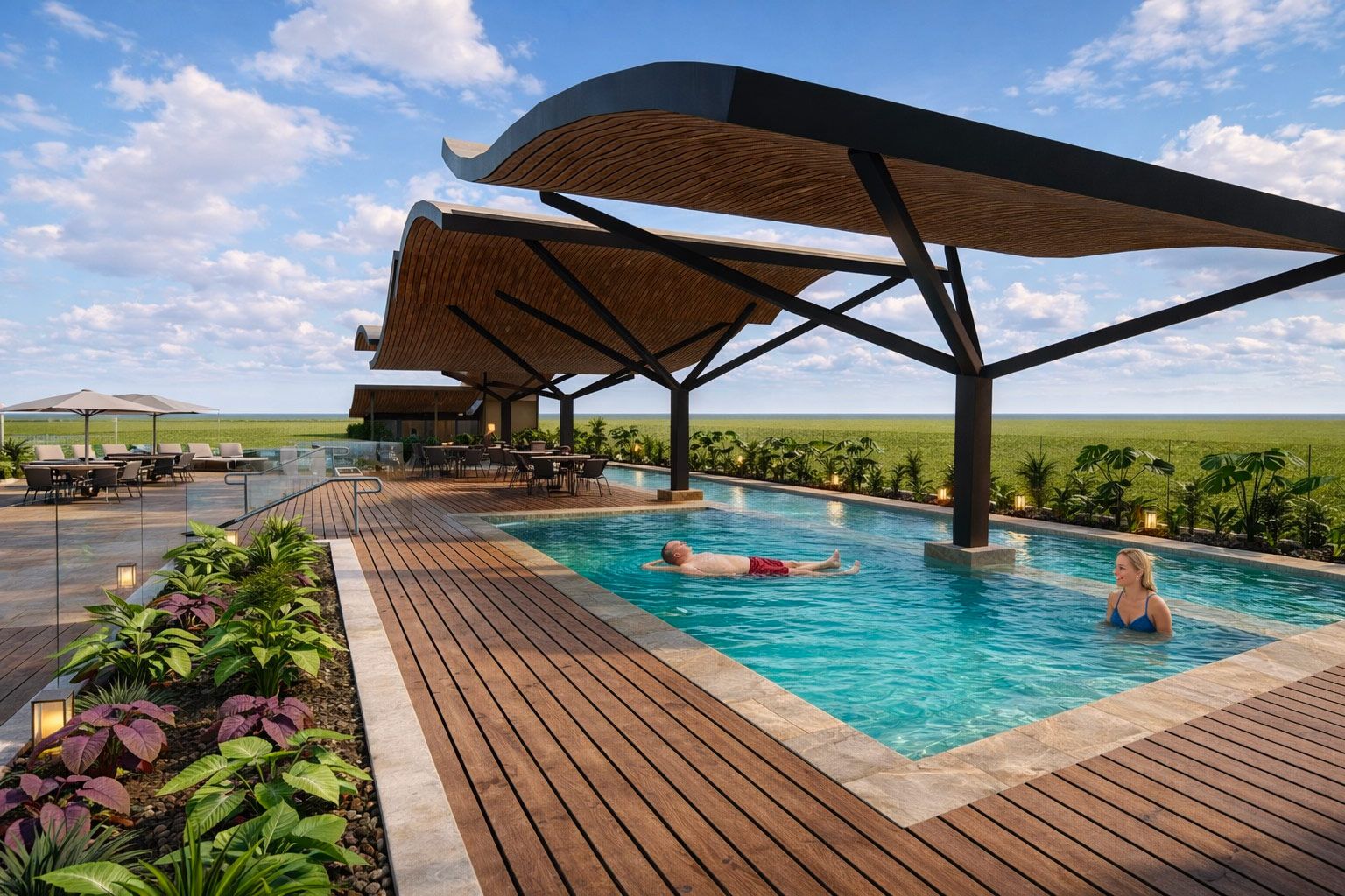 A pool with wooden decking and thatched sunshades, set against a vast grassy plain under a clear blue sky.