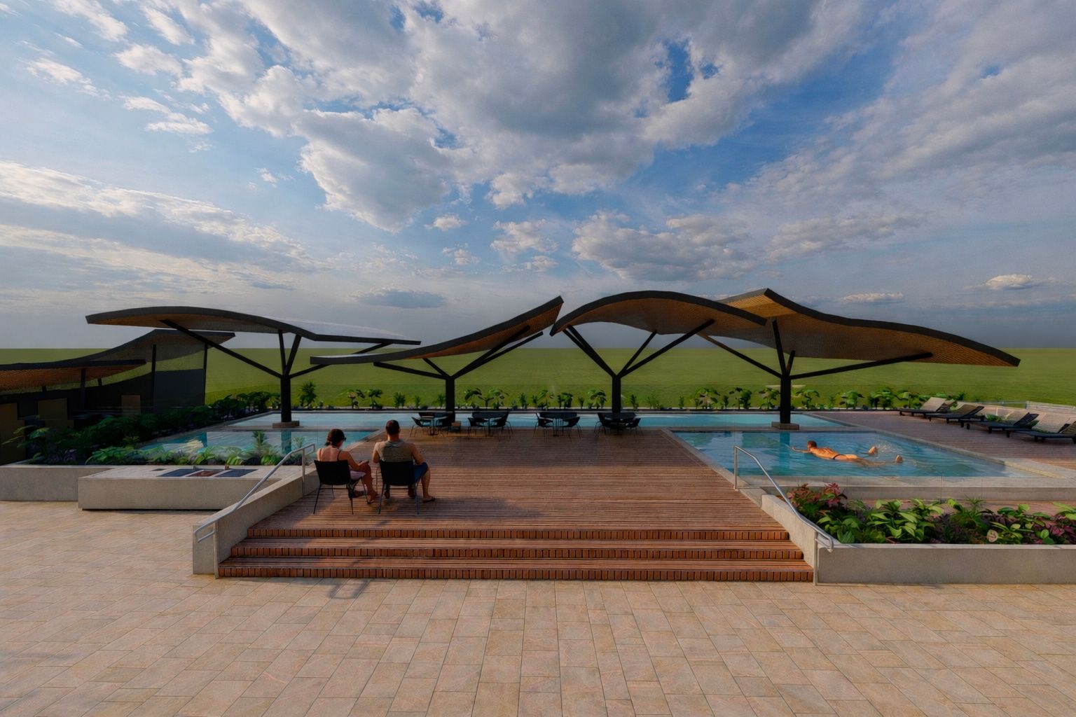 Two people sit on a wooden deck by a pool shaded by modern, leaf-shaped structures, overlooking a flat, grassy landscape.