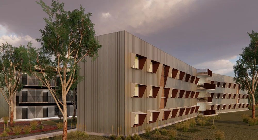 A modern, multi-story apartment building with metallic siding and protruding window shades, surrounded by trees.