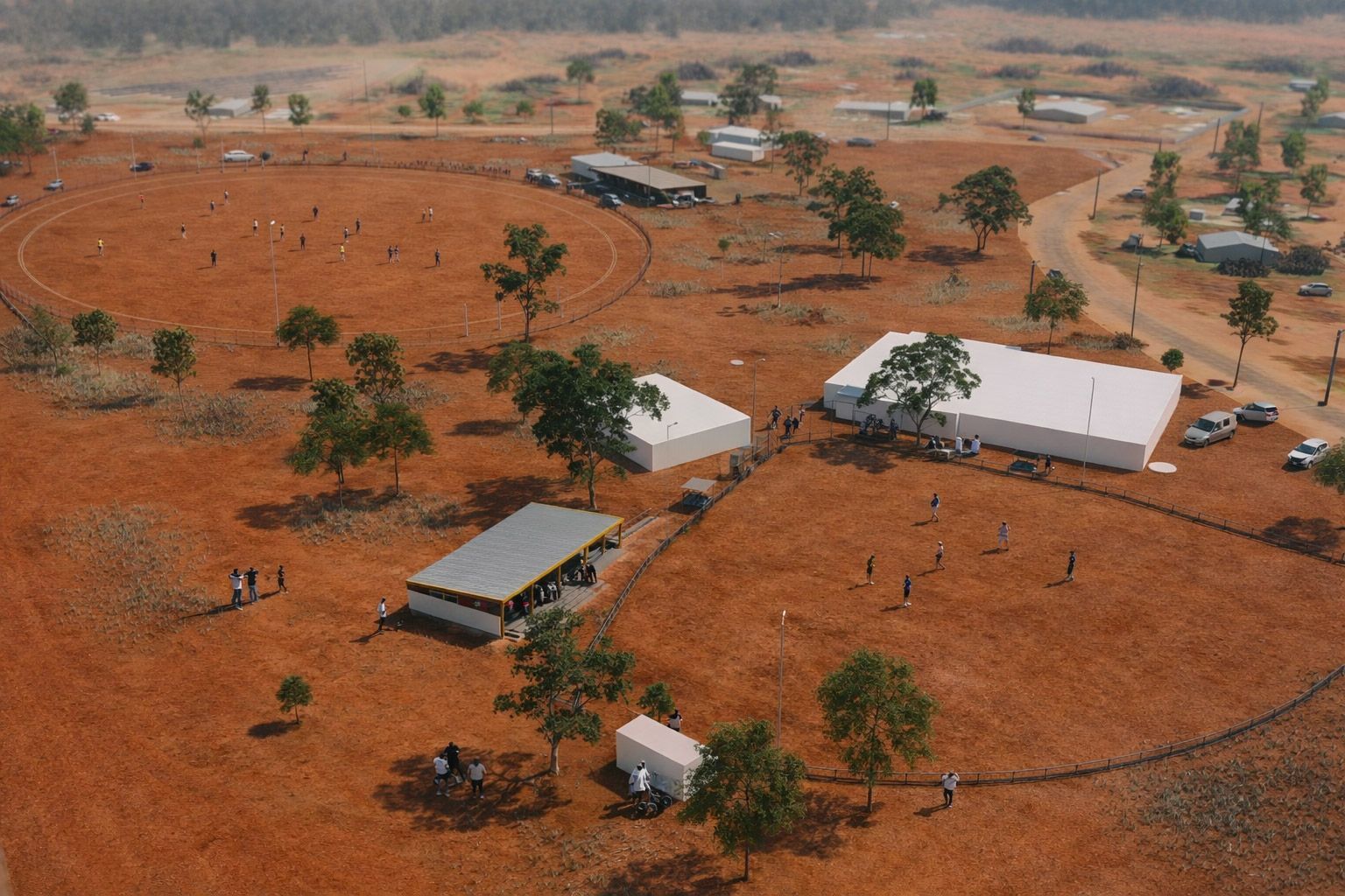 An aerial view of a dry, red-earthed camp with several rectangular white tents and structures, with people nearby.