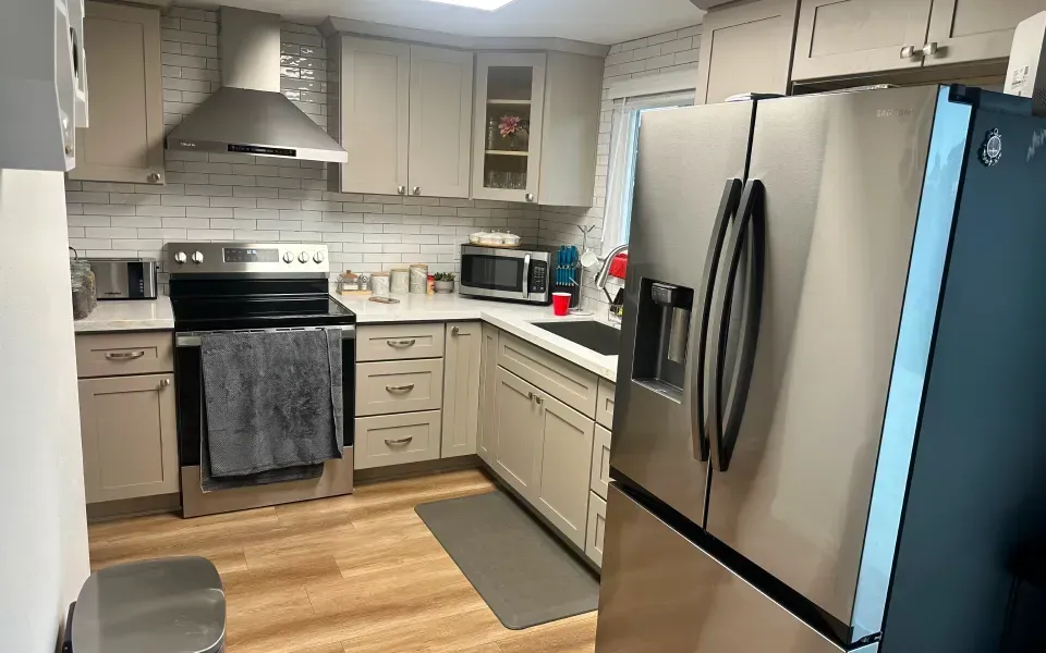 Modern kitchen with white cabinets, stainless steel appliances, and wood-look flooring