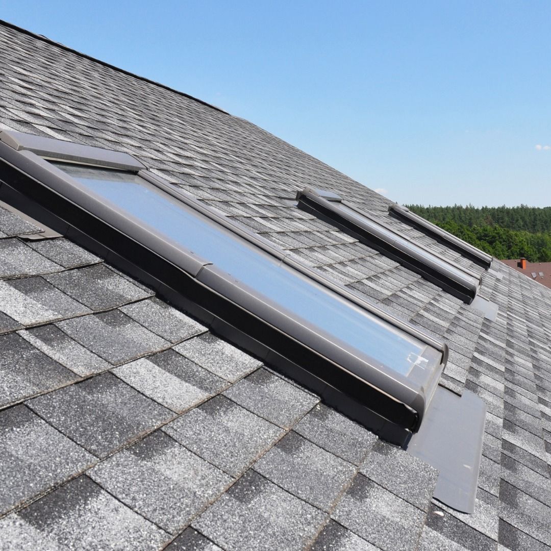 Solar roof skylights on a gray shingled roof under a clear blue sky.
