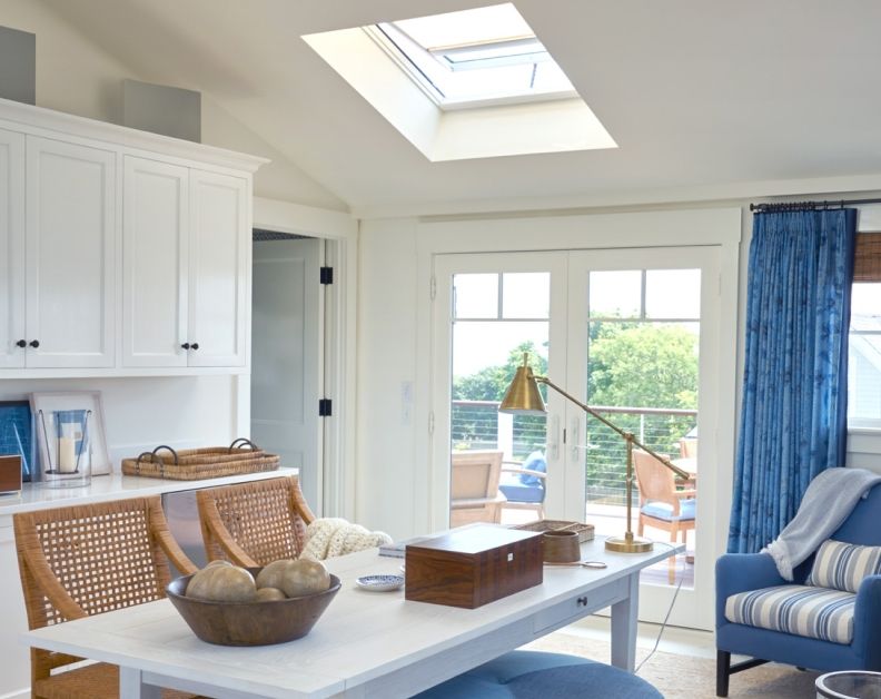 Bright white kitchen and dining area with skylight, blue chairs, and French doors to a patio.
