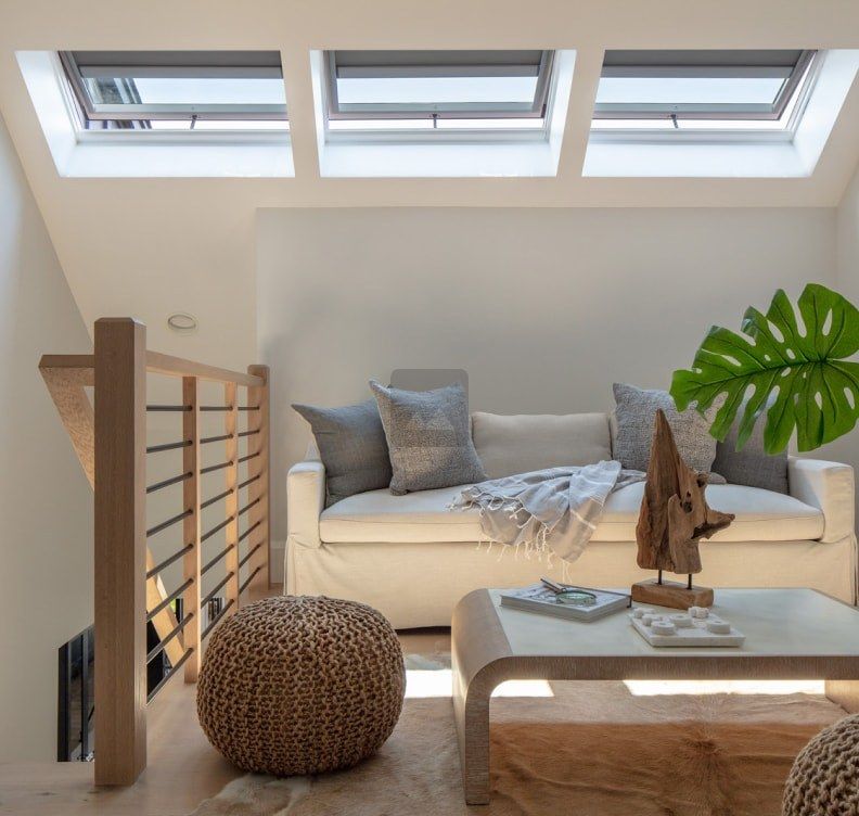 Cozy loft living room with skylights, white sofa, wooden coffee table, and woven pouf