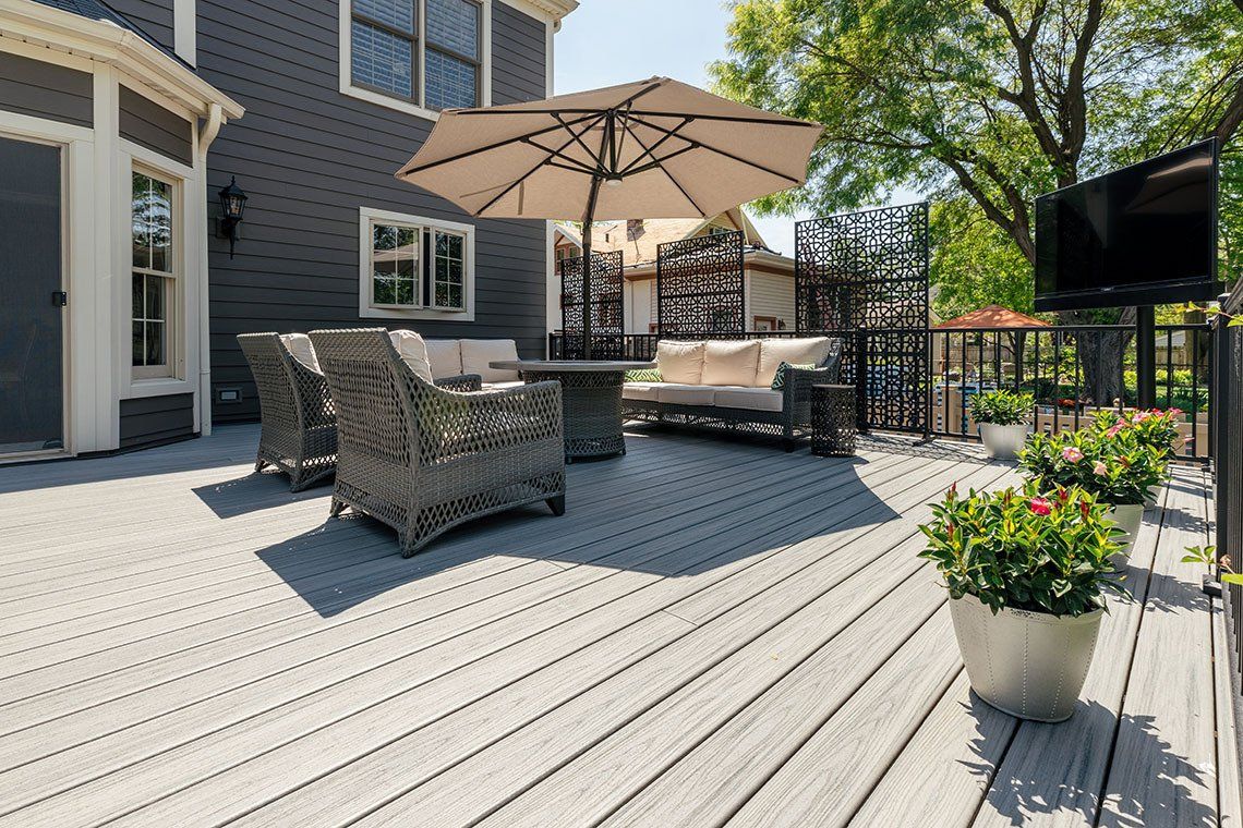 A large deck with a couch , chairs , and umbrella.