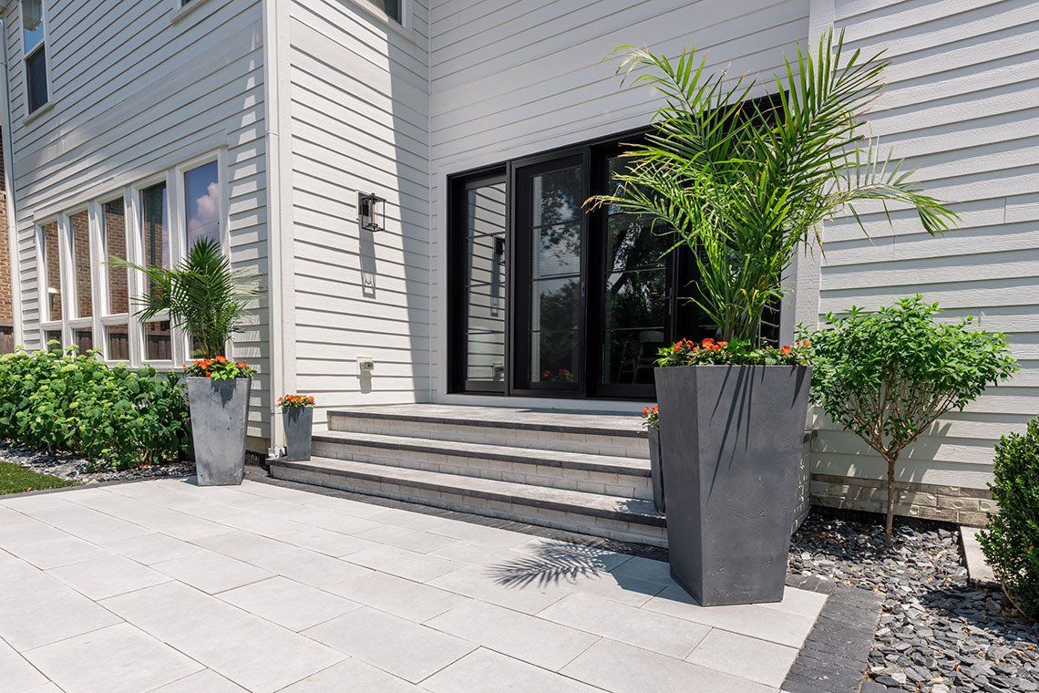 A white house with a patio and planters in front of it.