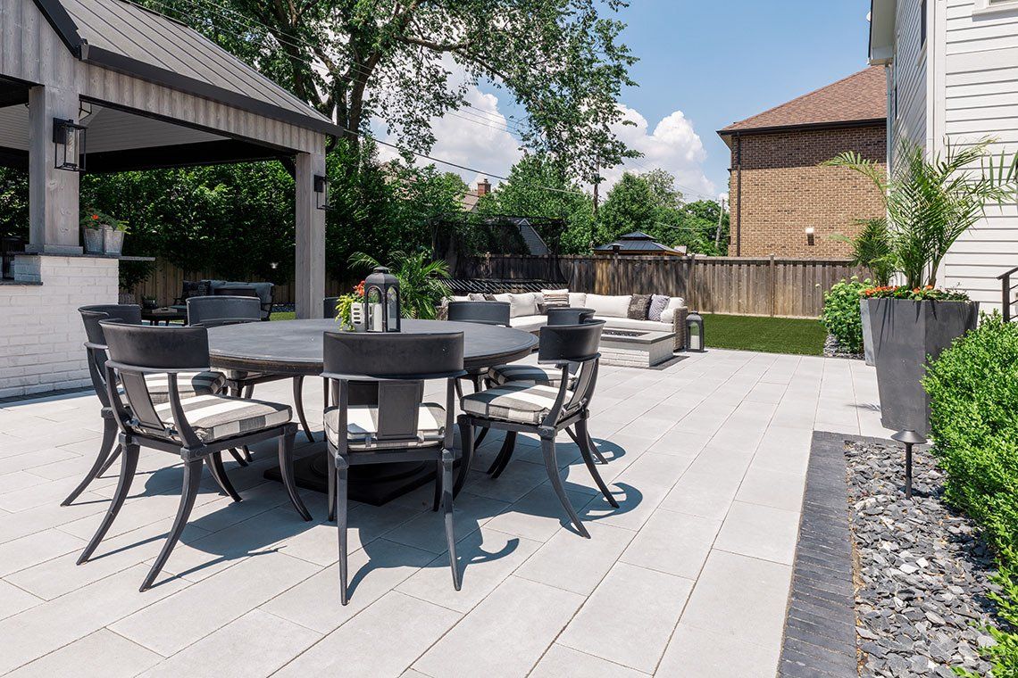 There is a table and chairs on the patio in the backyard.