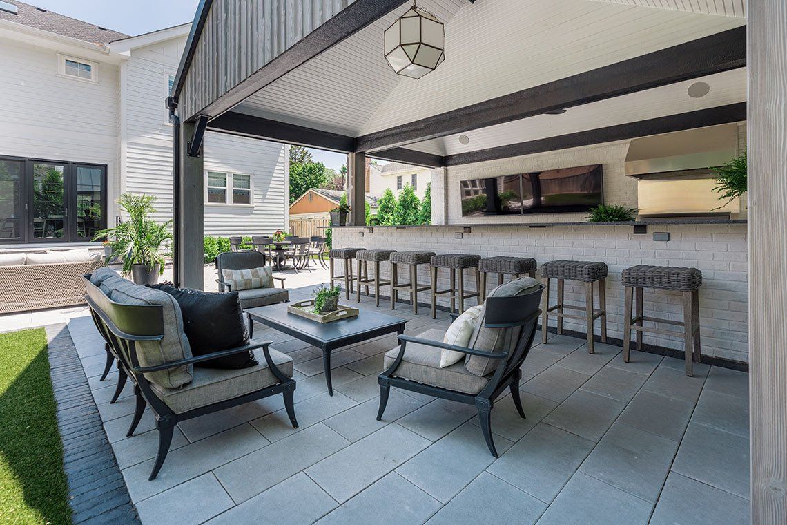 A patio with chairs , tables and stools under a canopy.