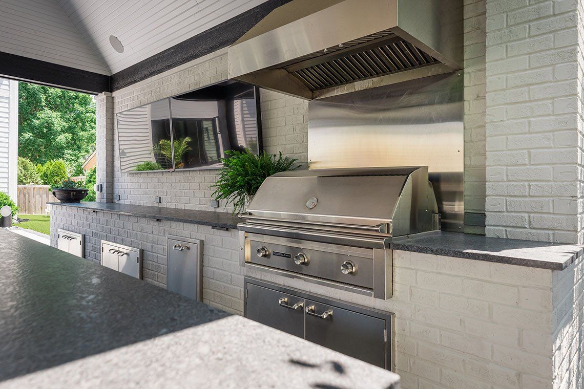 An outdoor kitchen with a stainless steel grill and a table.