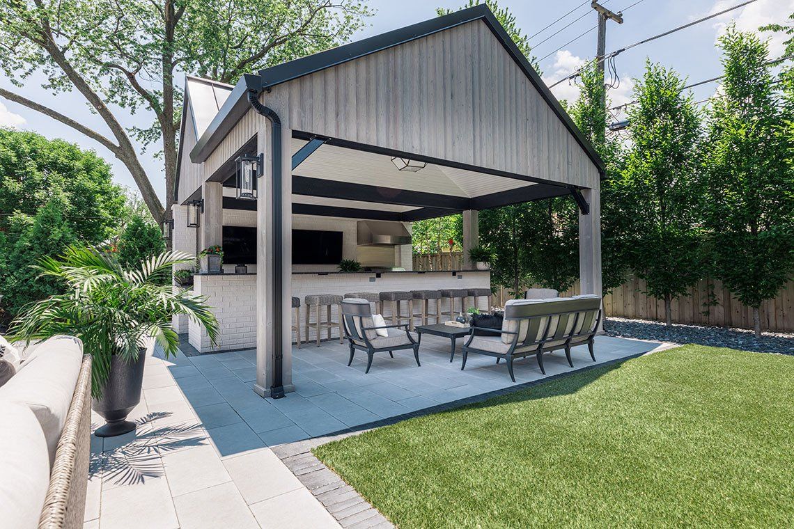 There is a gazebo in the backyard with a bar and chairs underneath it.