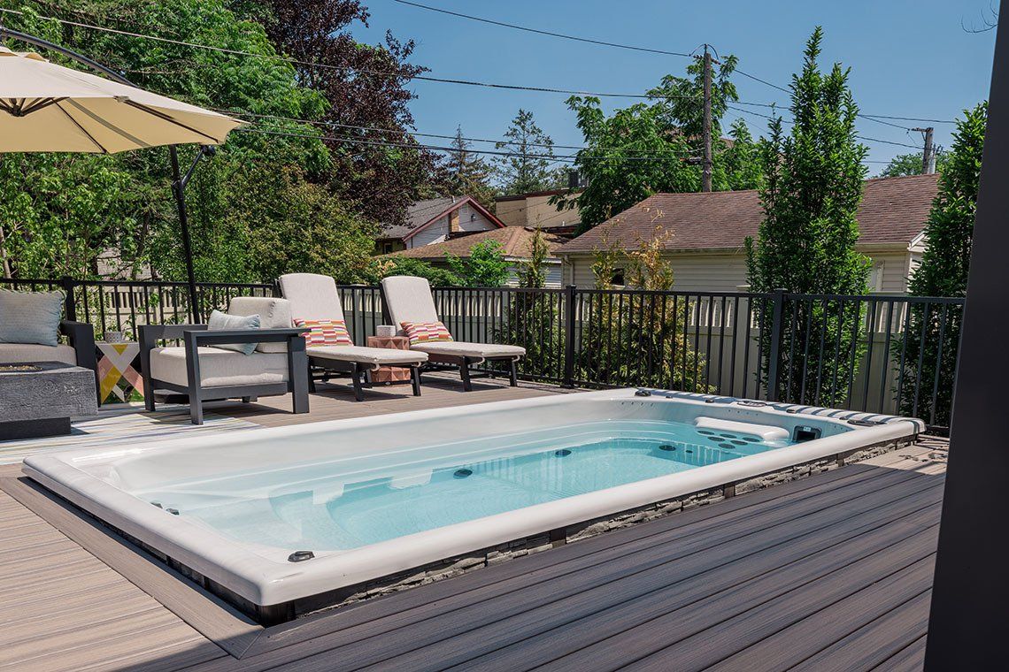 A large swimming pool is sitting on top of a wooden deck.
