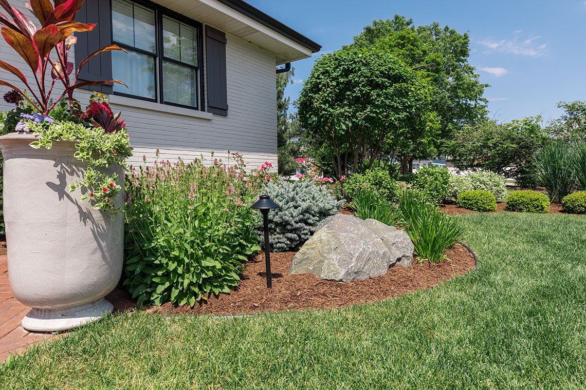 A house with a lush green lawn and a planter in front of it.