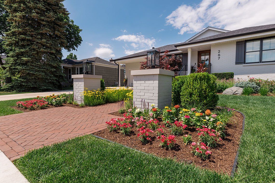 A white house with a lush green lawn and flowers in front of it.