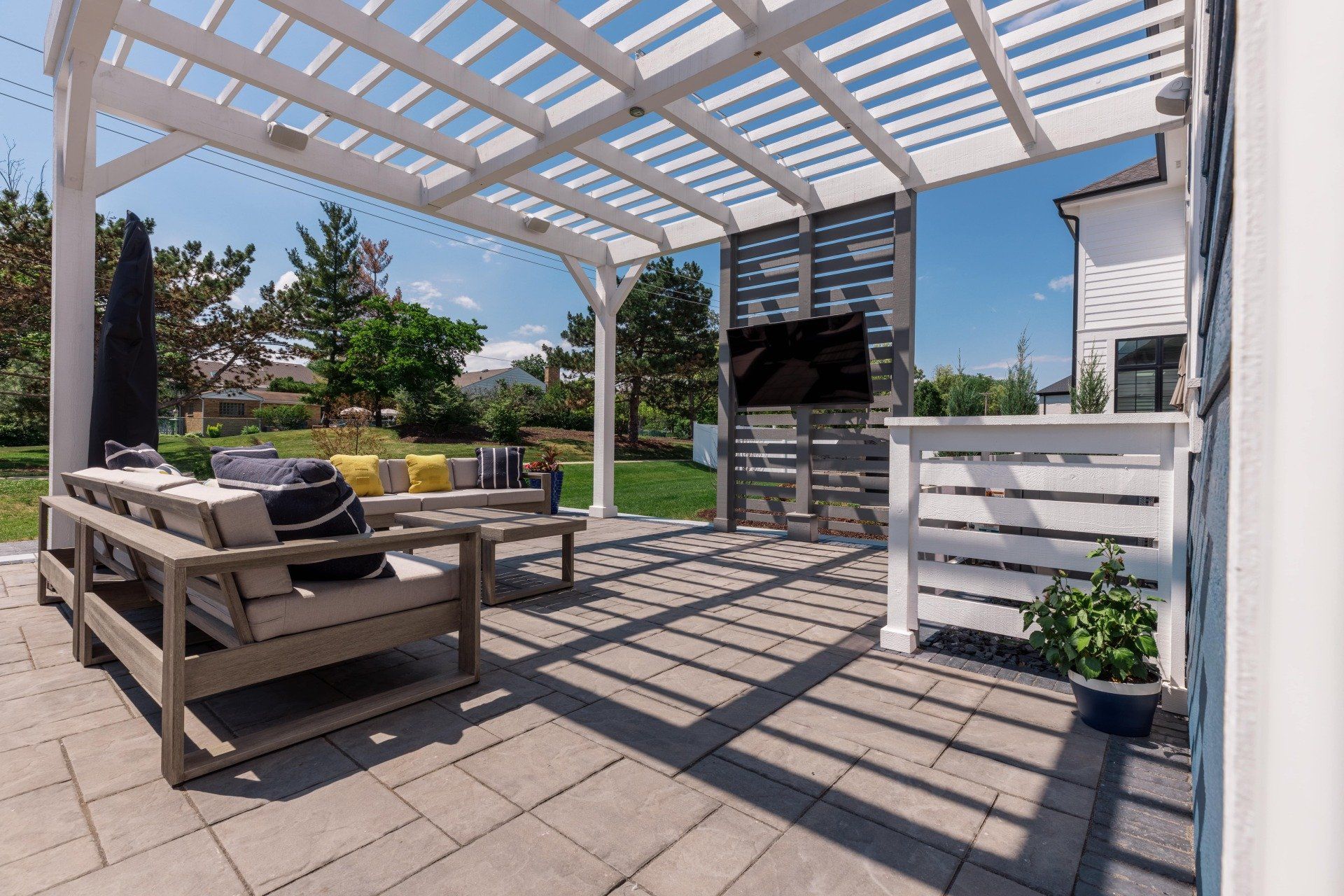 A patio with a pergola and a flat screen tv.