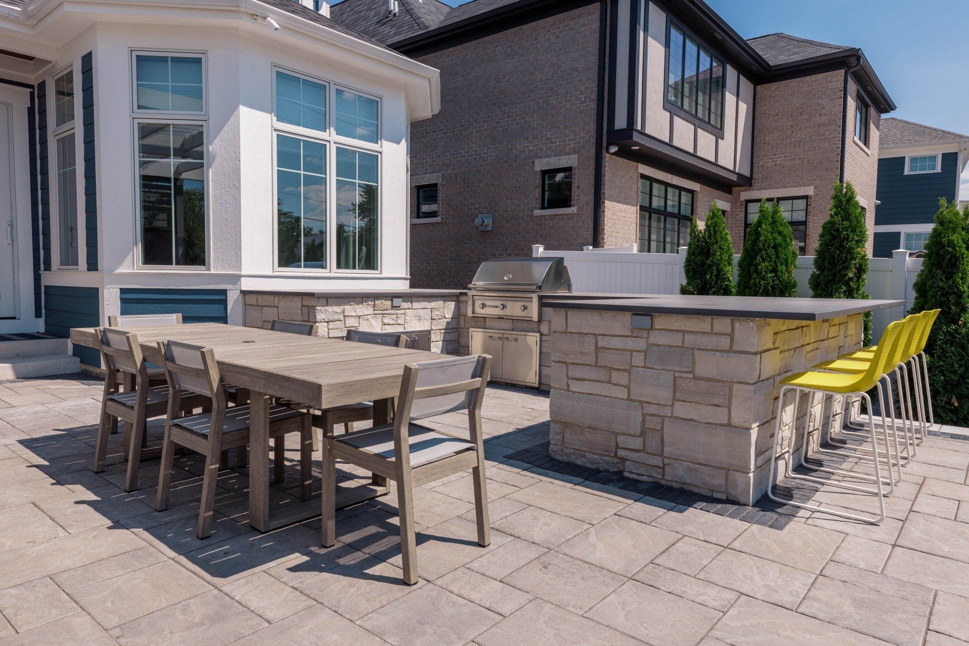 A patio with a table and chairs and a grill in front of a house.