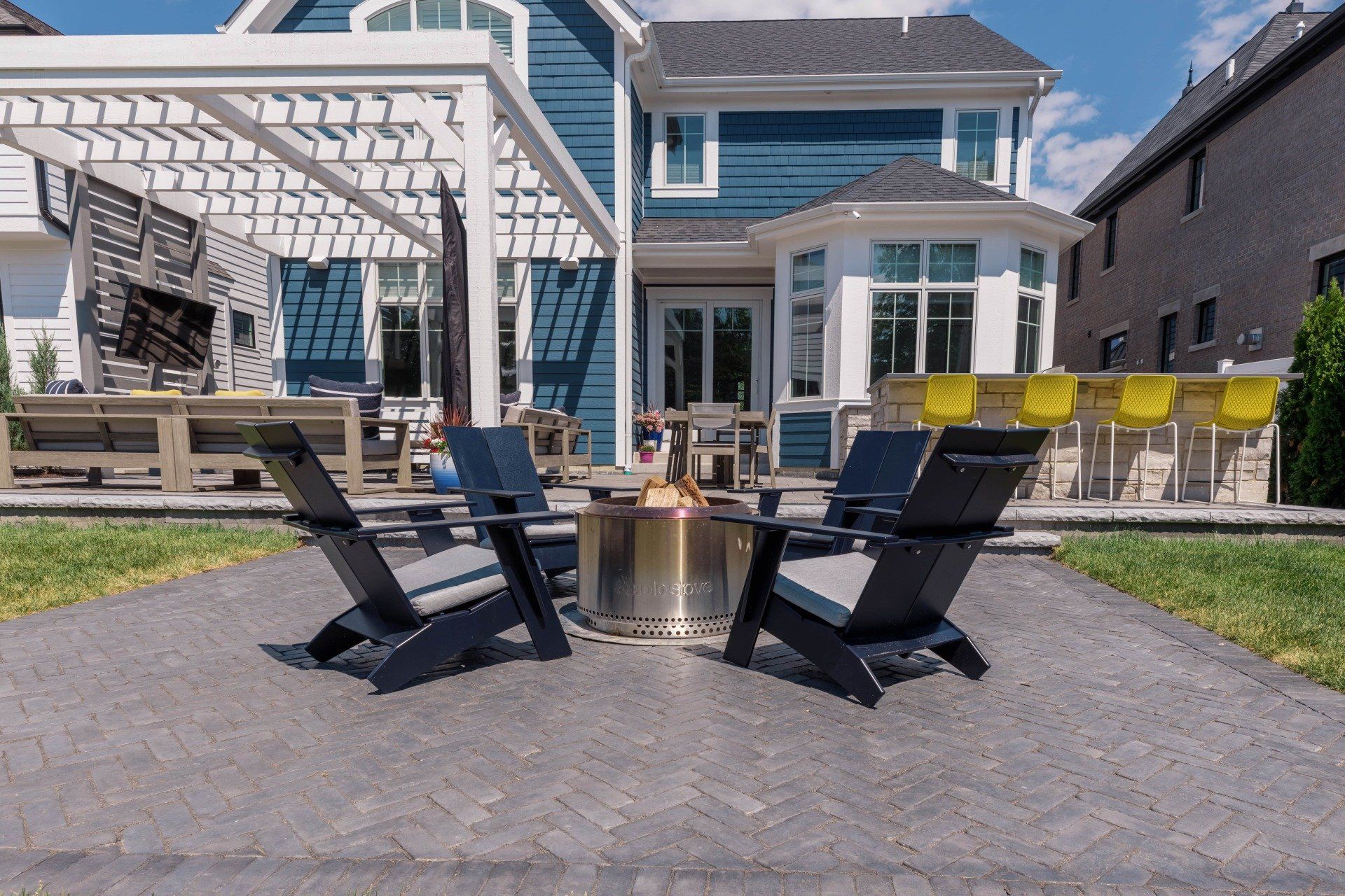 A patio with chairs and a fire pit in front of a house.