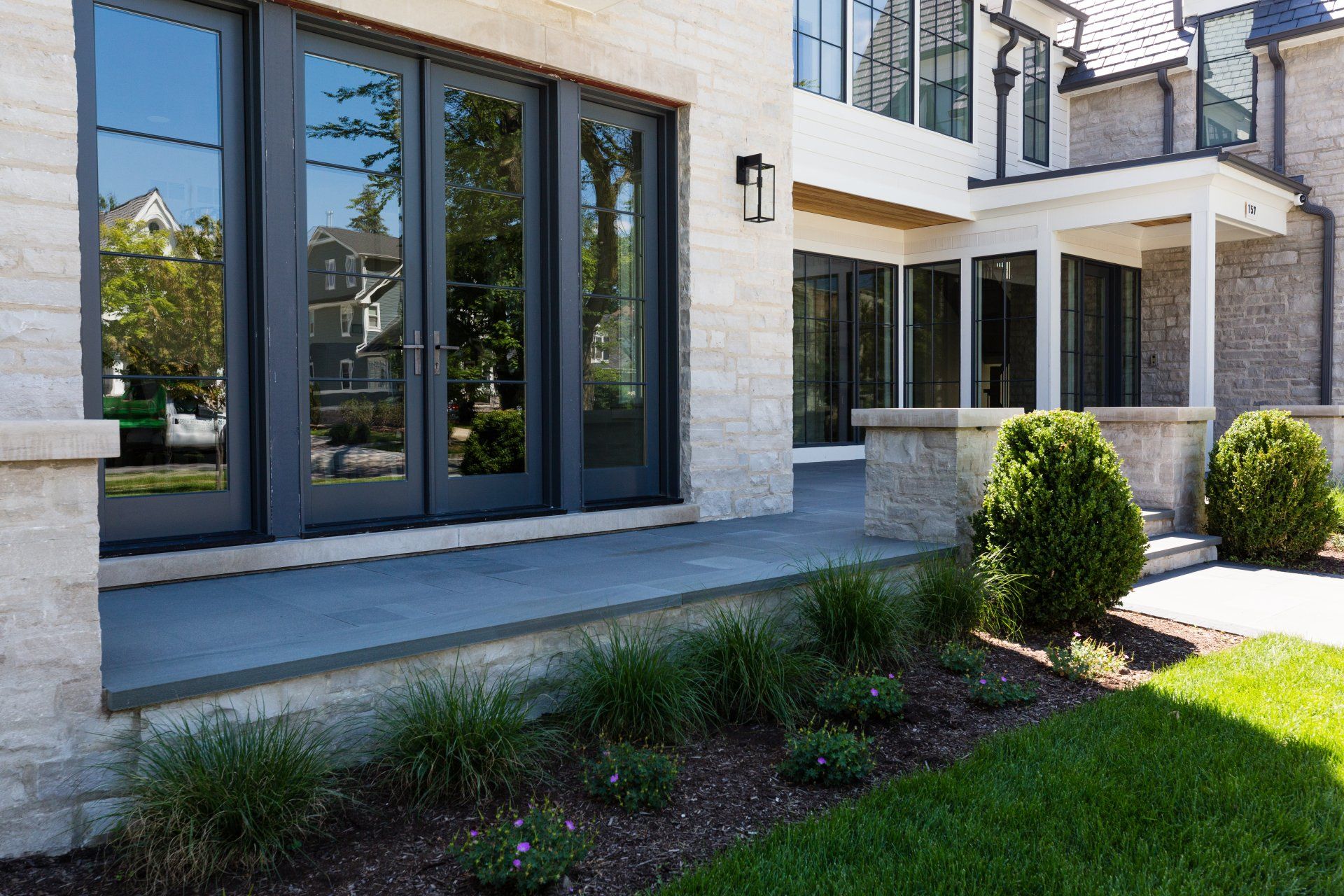 A large house with a lot of windows and shrubs in front of it.