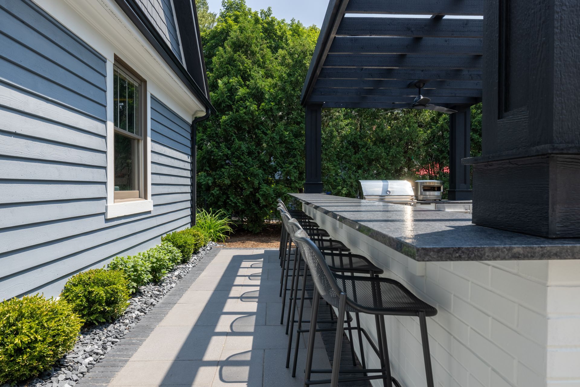 A patio with a bar and stools in front of a house.