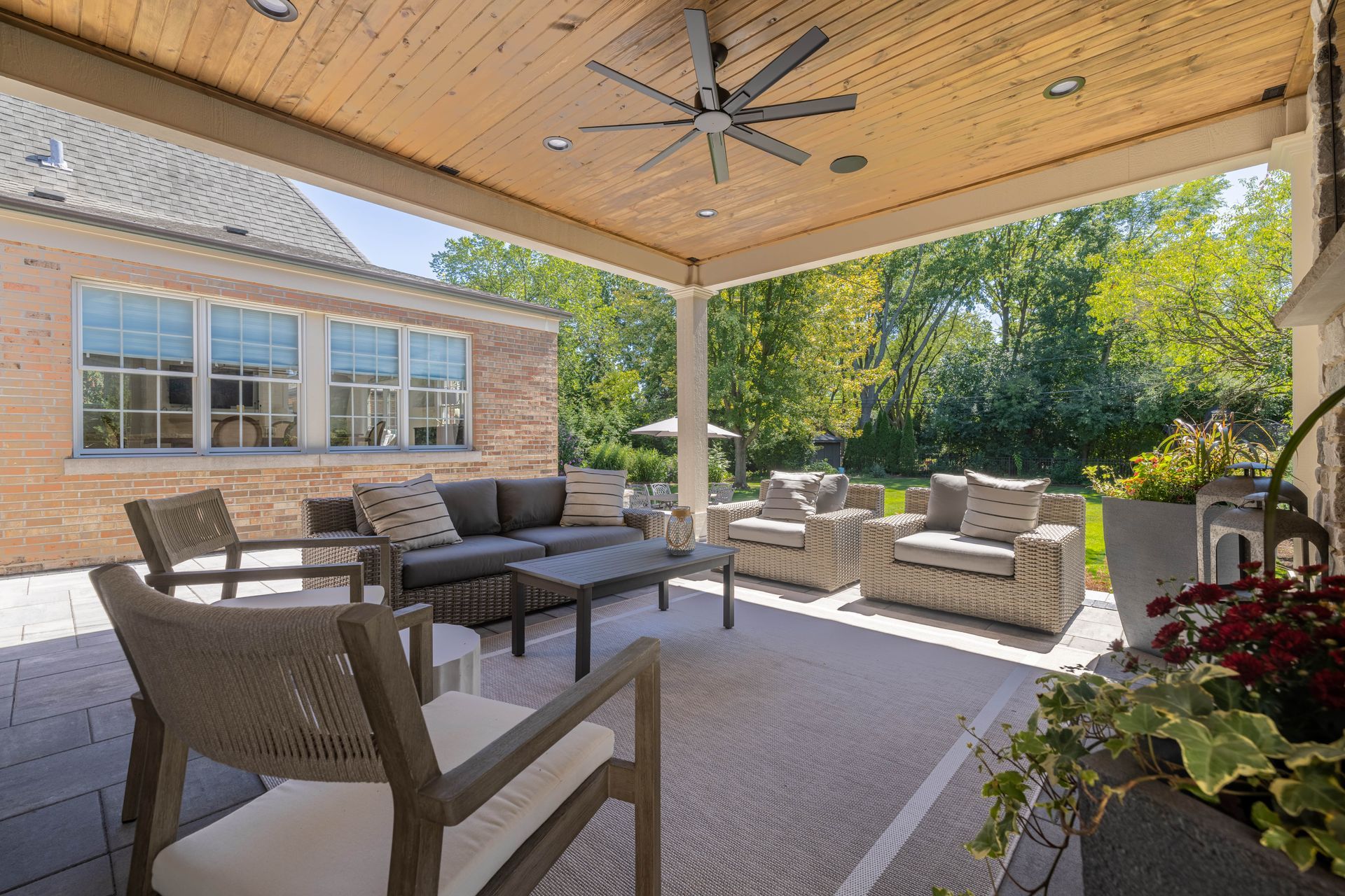 A patio with a couch , chairs , a table and a ceiling fan.