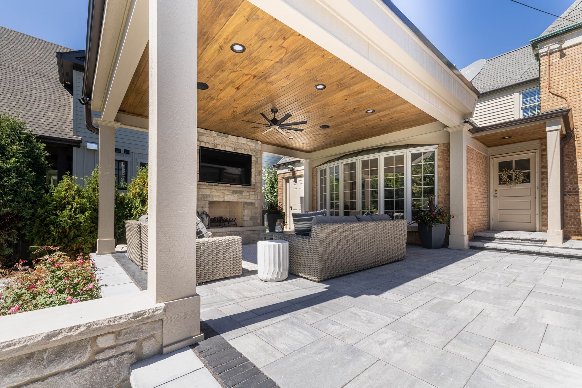A large covered patio with a fireplace and a ceiling fan.