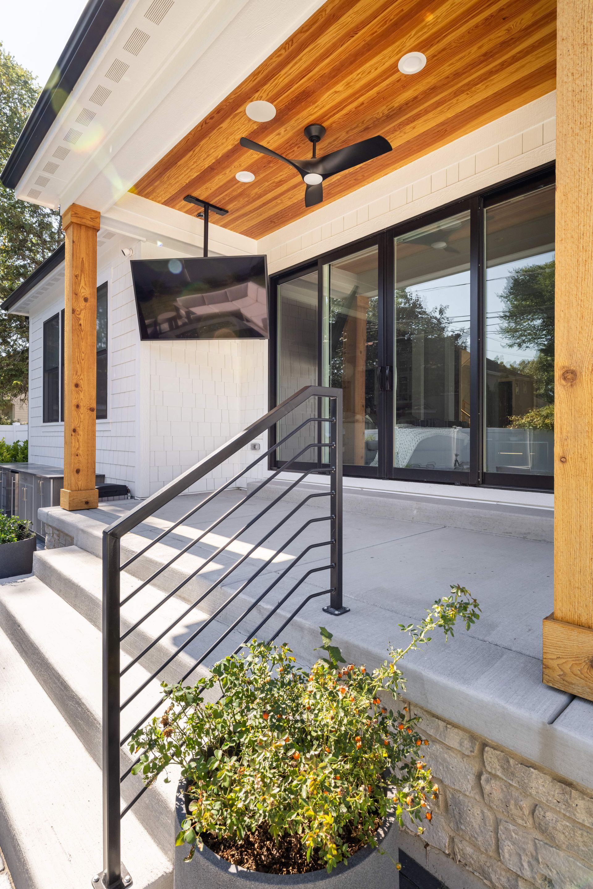A porch with a ceiling fan and a flat screen tv on it.
