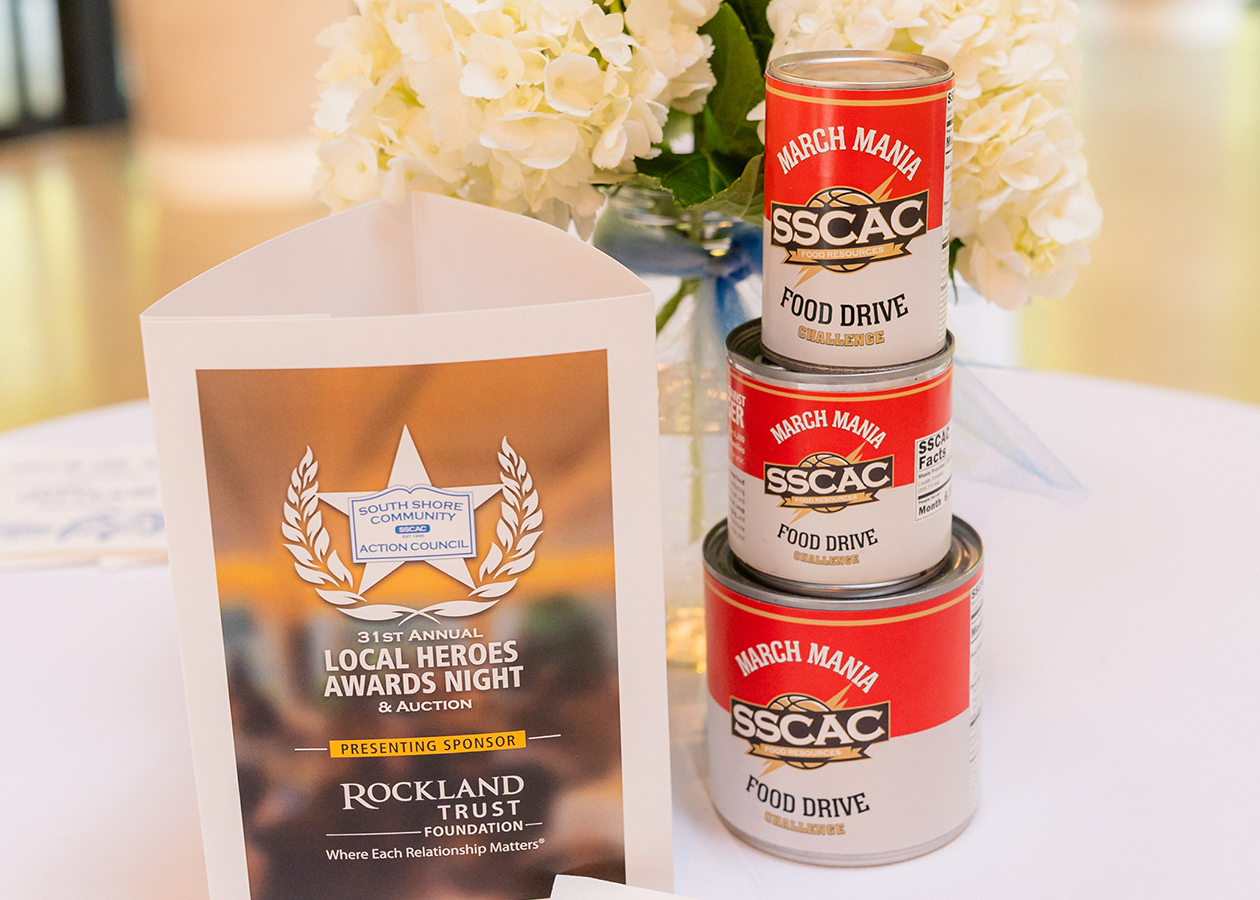 Award plaque beside stacked SSAC cans and a white floral arrangement on a table.