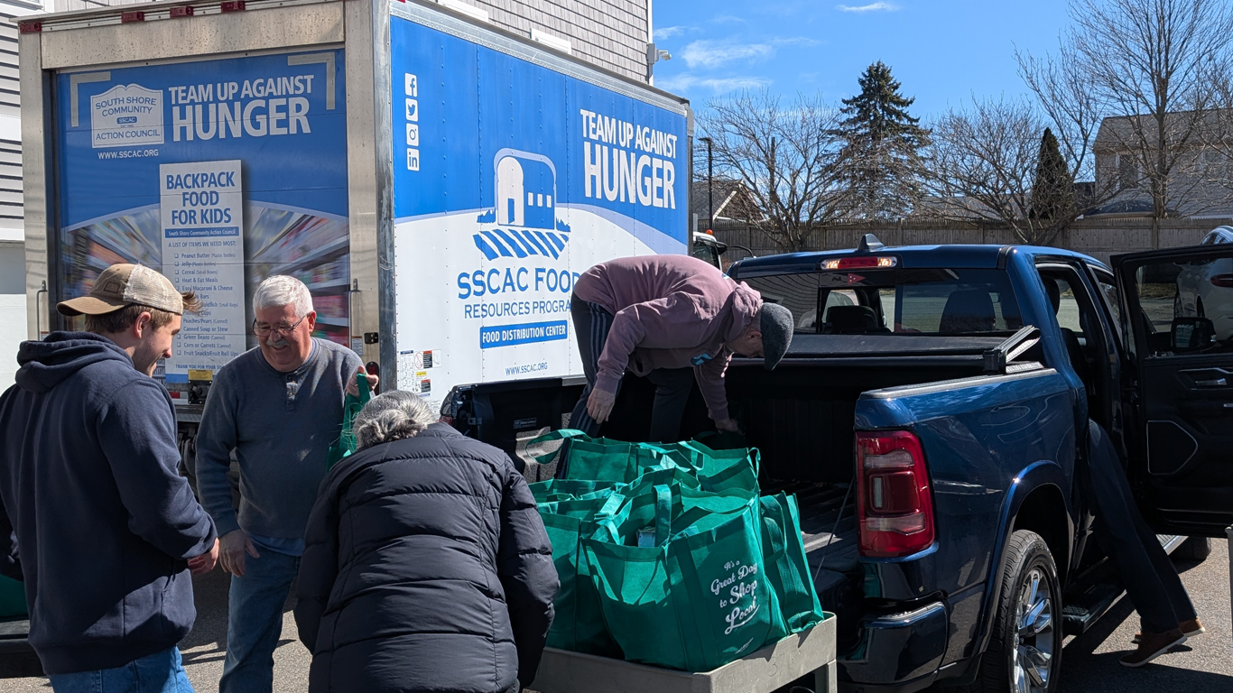People loading green grocery bags from a