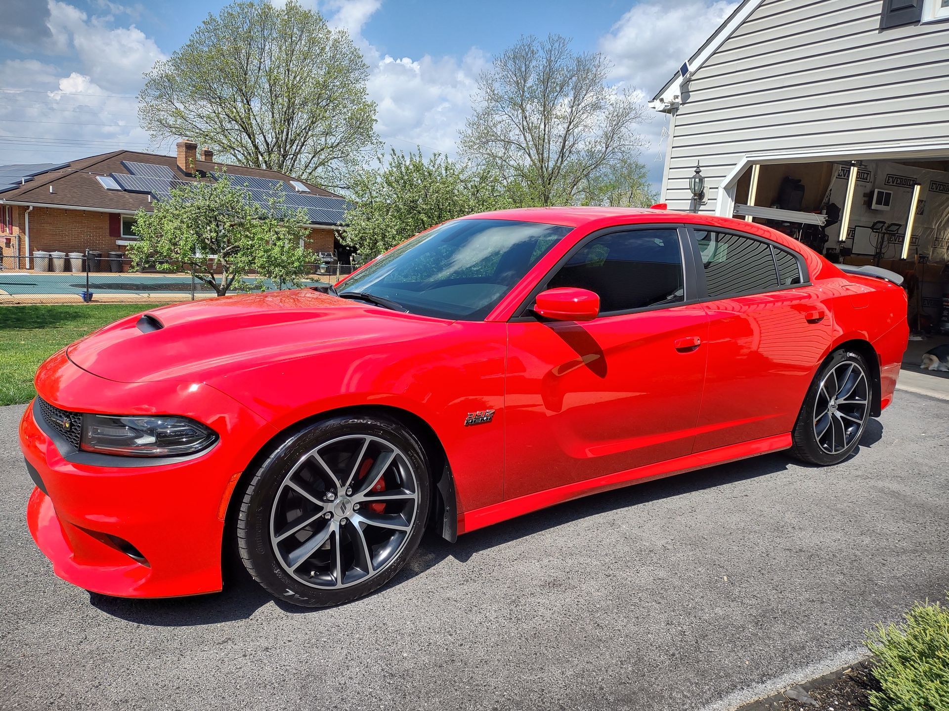 A red dodge charger is parked in front of a garage.