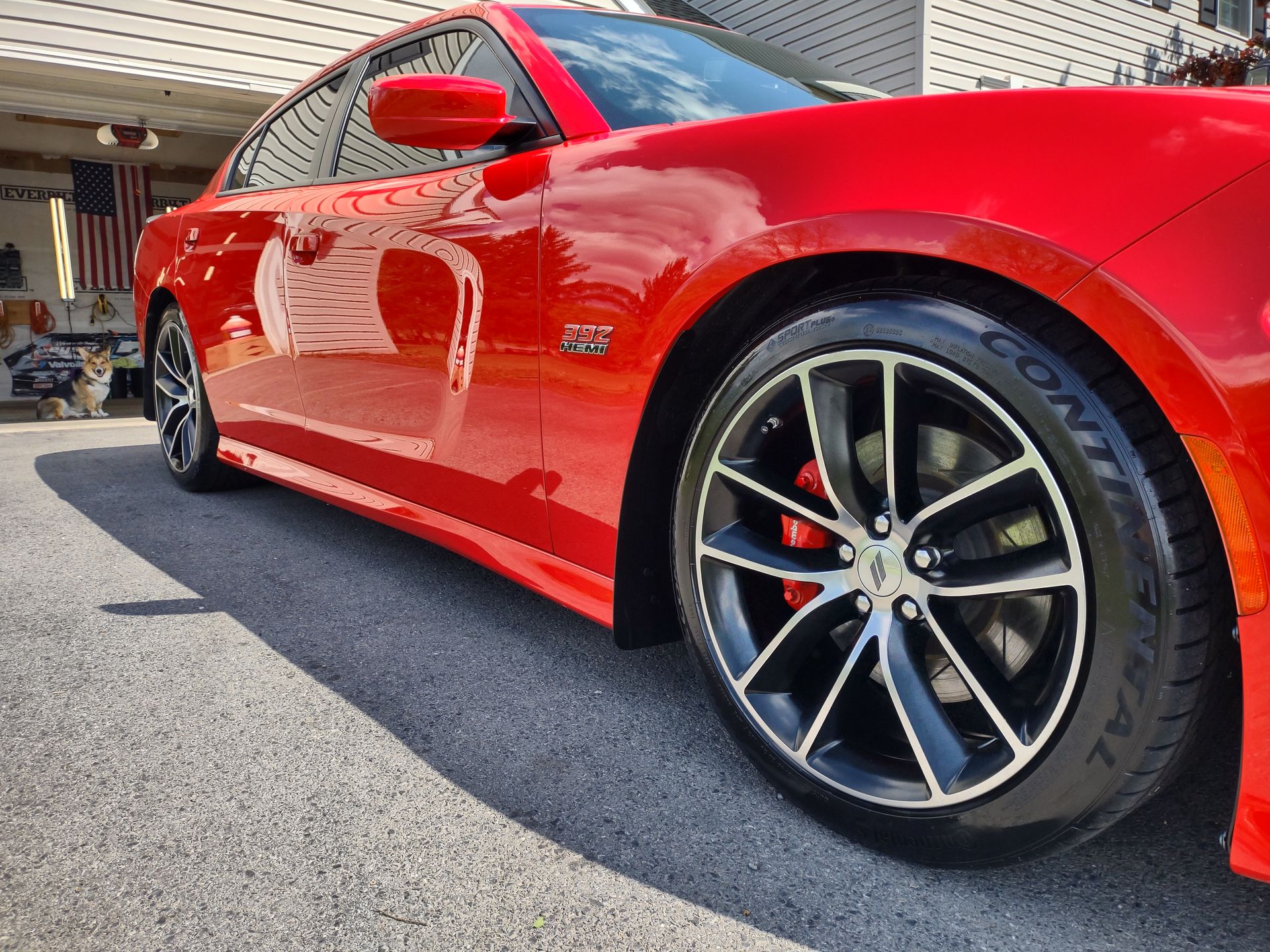 A red car with continental tires is parked in a garage