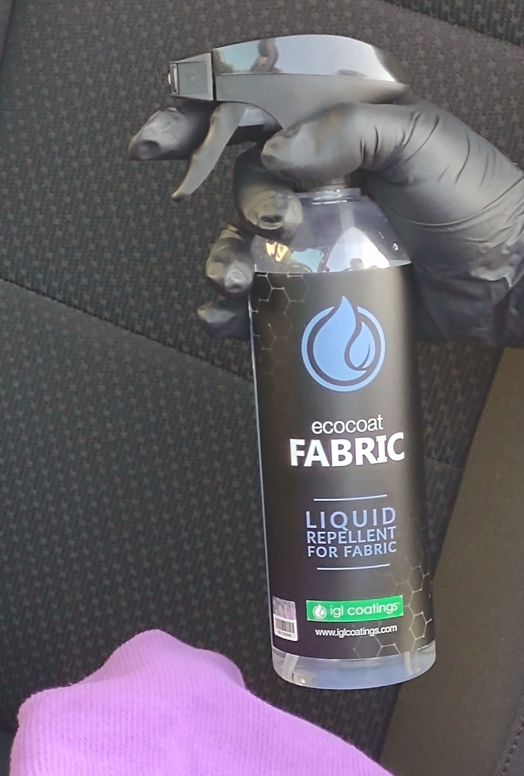 A person is holding a bottle of fabric liquid repellent