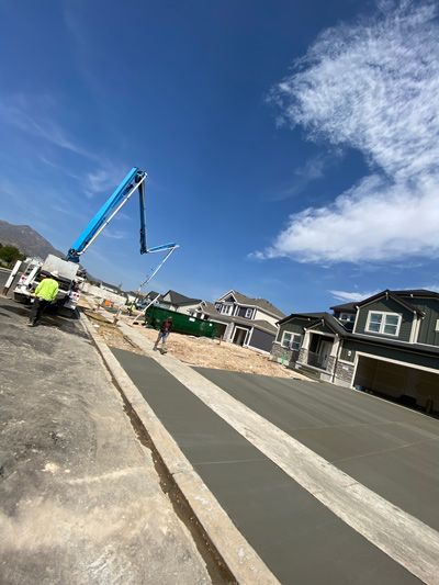 Construction workers and blue concrete pump truck at a new house build site under a bright blue sky