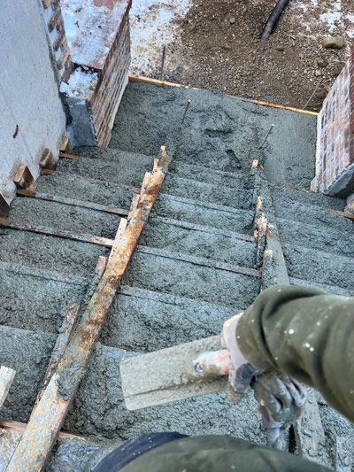 Person descending a narrow, weathered concrete staircase with wooden planks at the sides