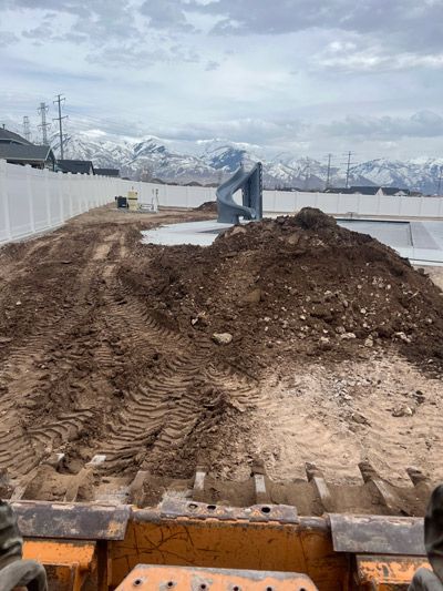 Mud construction path with tire tracks, snowbanks, and mountains in the distance